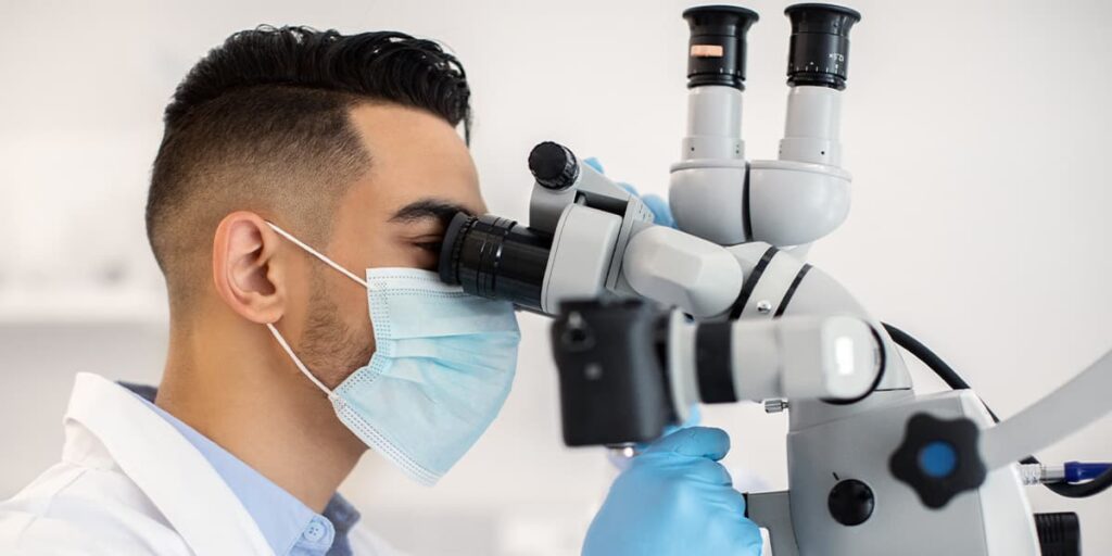 A doctor examining a histology sample under a microscope.
